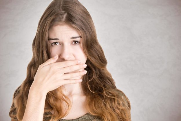 causes of bad breath woman with hand over mouth suffering from what causes of bad breath