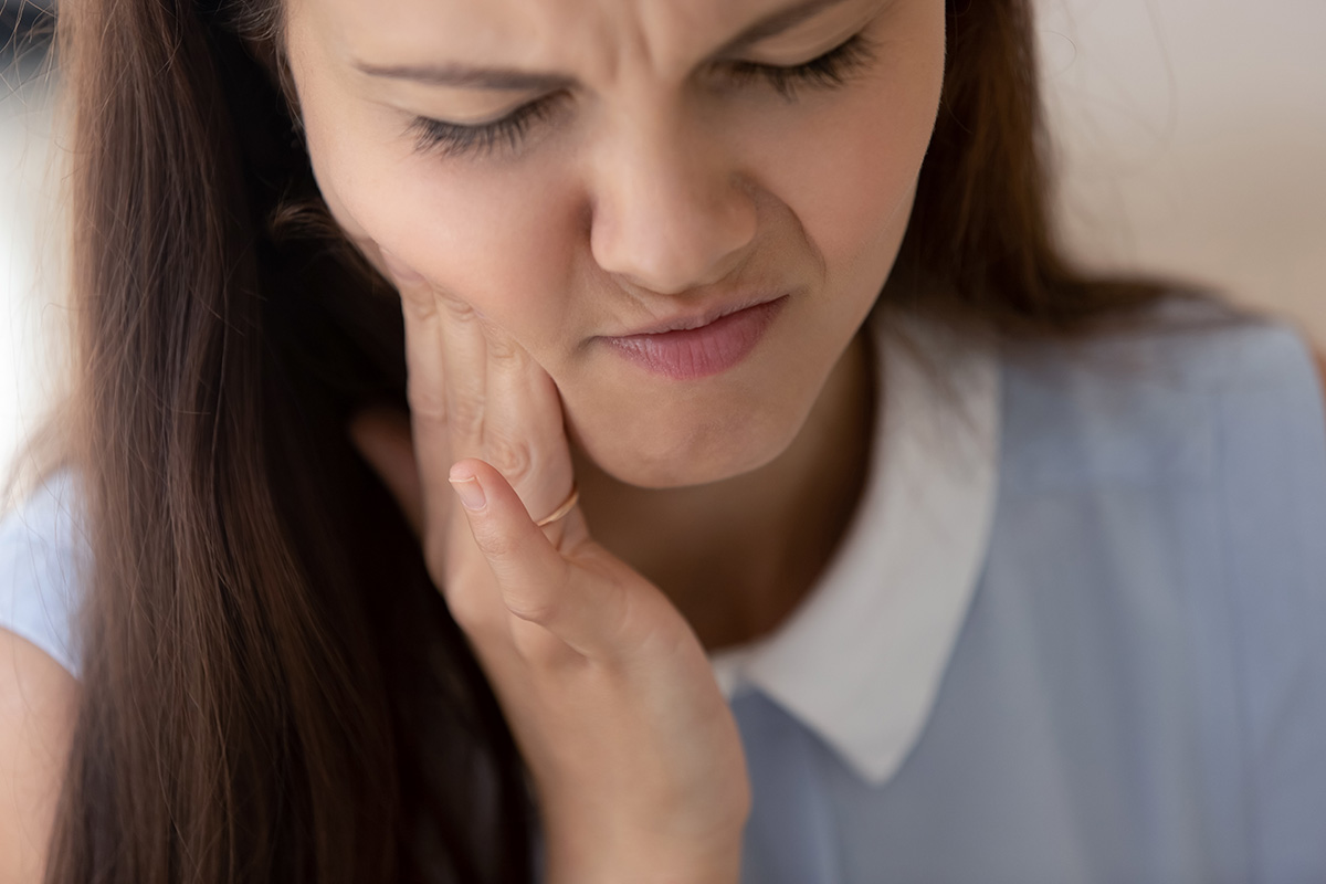 girl holding jaw in pain not knowing How Does Tooth Decay Develop