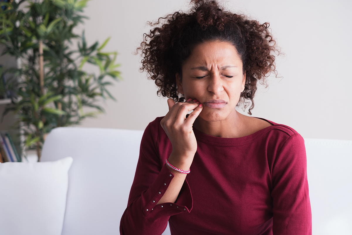 a woman feeling dental pain scared about gum disease