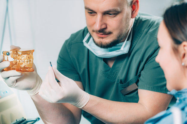 4 Benefits of Dental Implants (6) dentist explaining a dental implant